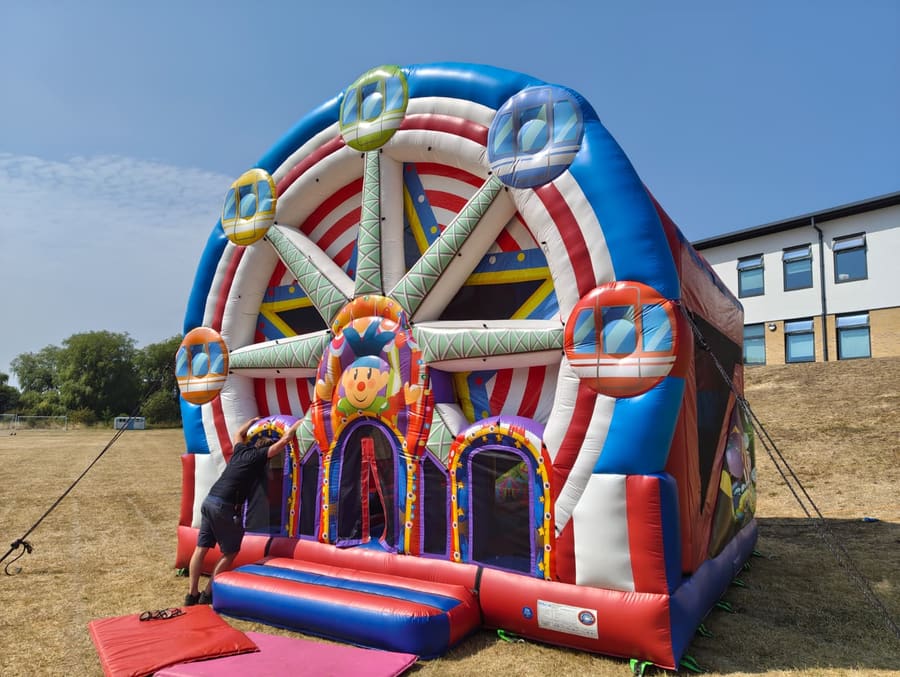 A large inflatable big-wheel bouncy castle being set up on the school field